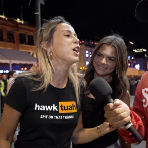 Női modell Hawk Tuah Spit on That Thang pólóban interjú közben
