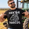 Férfi modell fekete Hektár Harcos traktoros pólóban, mezőgazdasági területen traktor mellett.