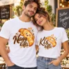 Szerelmes pár fehér Kis kifli és Nagy kifli páros pólóban, mosolygó croissant-grafikákkal és szívekkel.