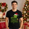 Fiatal férfi fekete Csak a gyászmeg a szenvedés Grinch Pólóban, zöld karácsonyi karakterrel és humoros felirattal.