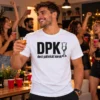 DPK deci pálinkát kérek póló fehér színben, fekete felirattal és pálinkáspohár grafikával, mosolygó férfi modellen, otthoni buliban.