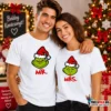 Fiatal pár fehér Grinch páros pólóban, MR. és MRS. feliratos zöld karácsonyi karaktergrafikával, ünnepi környezetben.