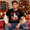 Fiatal férfi fekete Ho Ho Ho hol van a söröm pólóban, söröskorsót tartó Mikulás grafikával, karácsonyi környezetben.