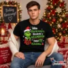 Fiatal férfi fekete Idén karácsonyra póló Grinch grafikával és „Idén karácsonyra mindenki a véleményem kapja ajándékba” felirattal, ünnepi környezetben.